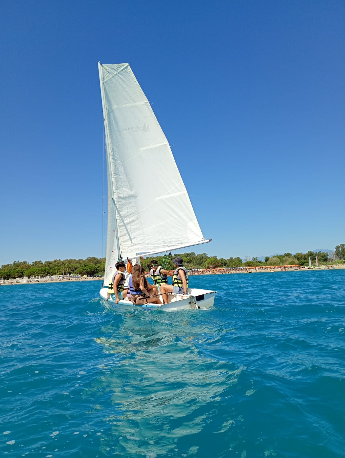 Ragazzi a bordo di una barca a vela sul mare azzurro